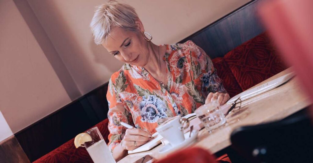 Laya Commenda sitzt vertieft beim Schreiben in einem Wiener Café