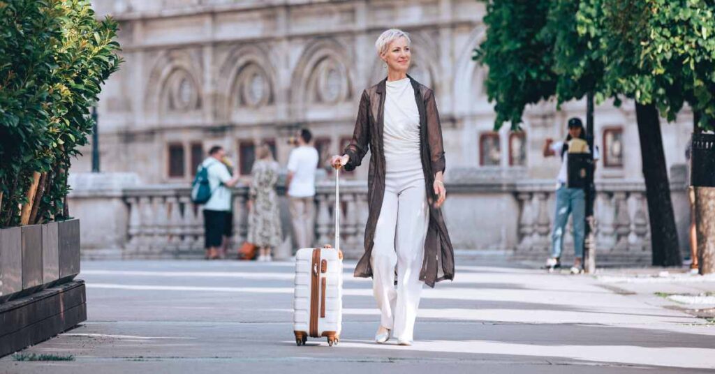 Mindset-Expertin Laya Commenda steht vor historischem Gebäude in Wien mit einem Trolley