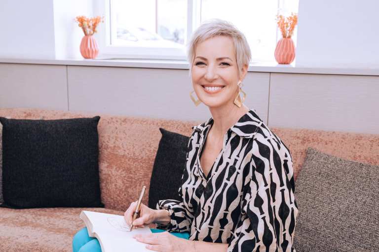 Mindset Expertin Laya Commenda sitzt schreibend auf der Couch