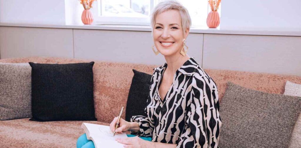 Laya Commenda Expertin für Mind-Management sitzt schreibend auf einem Sofa und primt ihren Mind