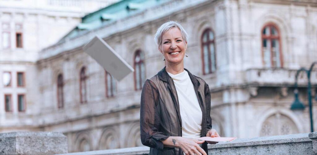 Mindset Expertin Laya Commenda grinst und wirft ein Journal in die Luft